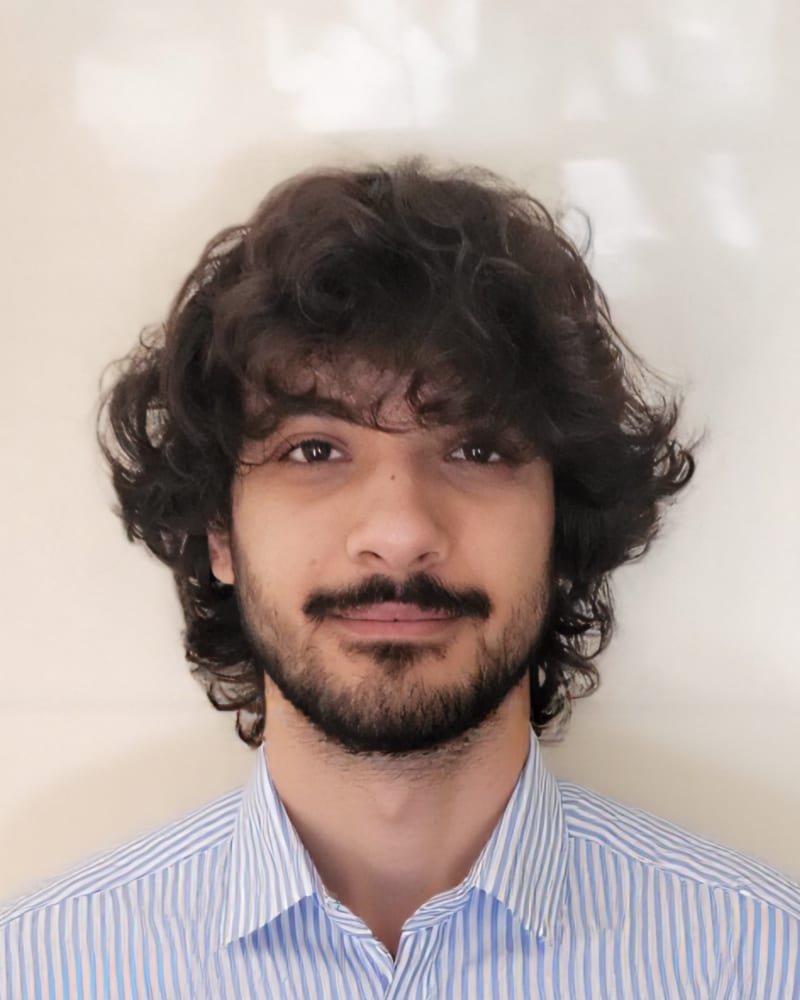 Lorenzo Martellone in a blue striped shirt, against a pale wall